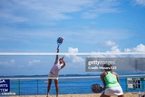 jovem bate em uma bola de tênis na praia - tênis esporte de raquete - fotografias e filmes do acervo
