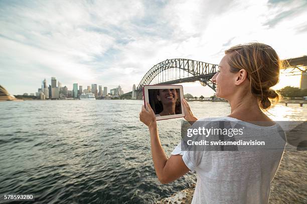 frau in sydney nutzt digitales tablet, um sydney skyline zu fotografieren - sydney harbour bridge stock-fotos und bilder