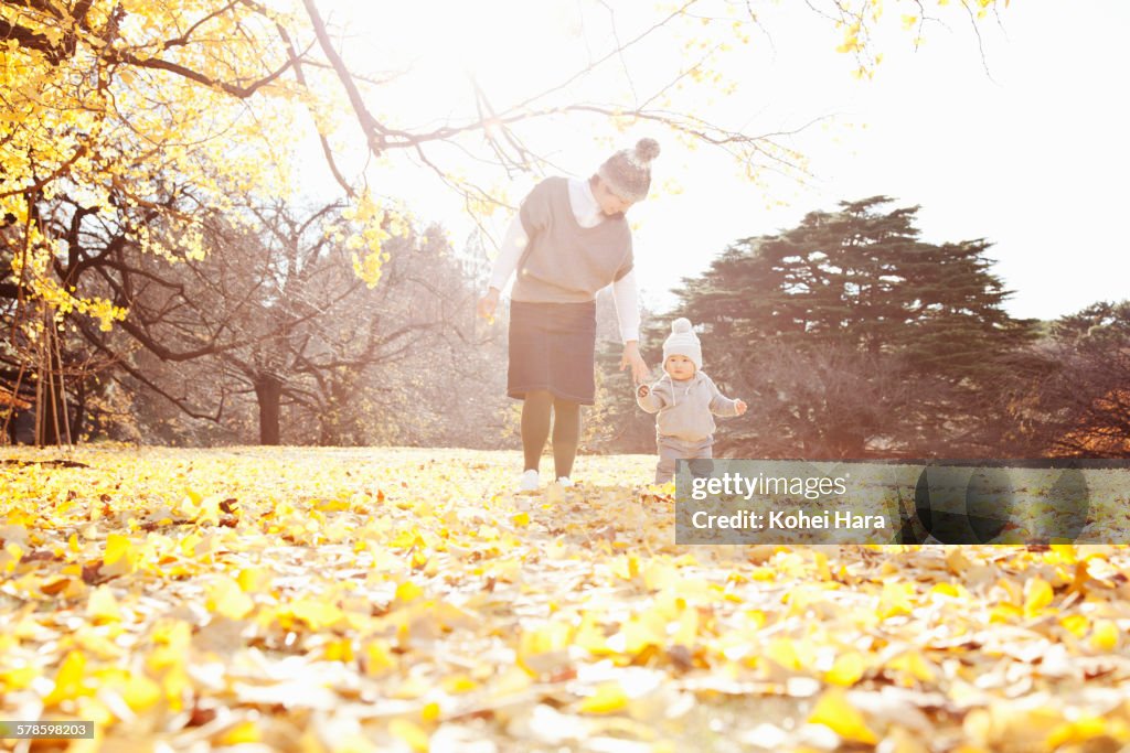 A baby and mother playing in the park in autumn