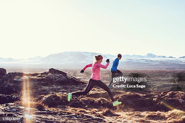 male and female free running through mountains - paar in sportkleidung stock-fotos und bilder