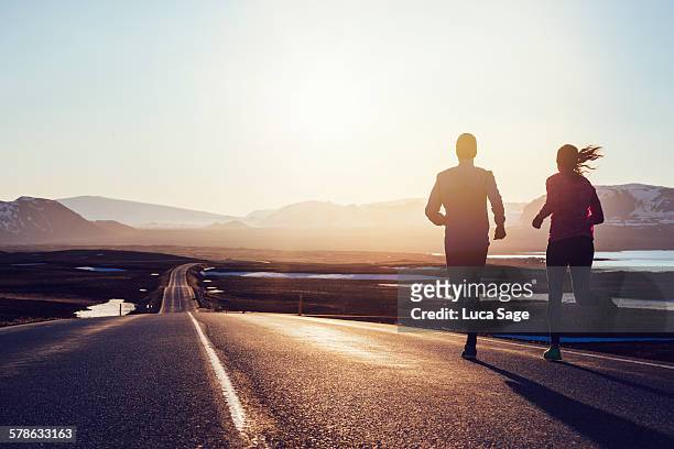 running along road at sunrise in iceland - fitness couple stockfoto's en -beelden