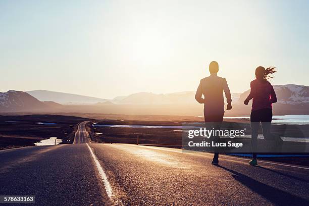 running along road at sunrise in iceland - couple running back stock pictures, royalty-free photos & images