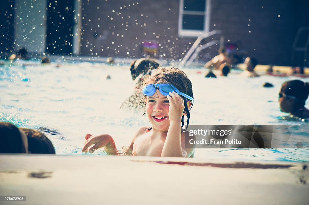 Boy in the pool smiling wearing goggles