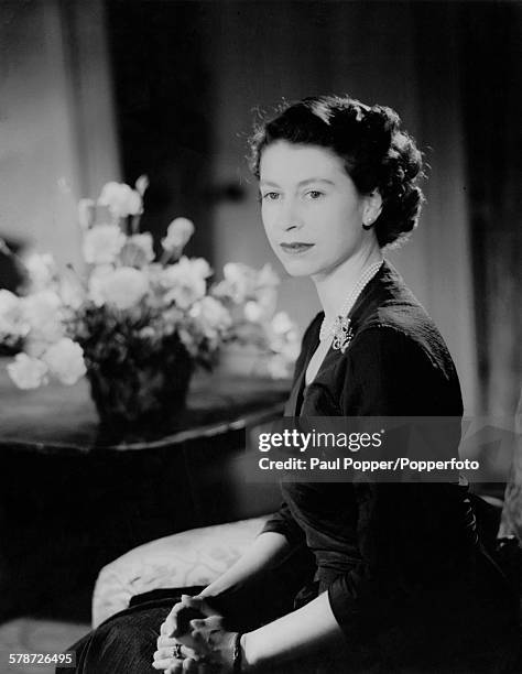 Princess Elizabeth in the drawing room at Clarence House, London, January 1952. She is wearing an afternoon dress of slate-blue figured silk.