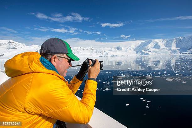 a passenger on the deck of the akademik sergey vavilov, an ice strengthened ship on an expedition cruise to antarctica, off the antarctic peninsular at the gerlache strait. the antarctic peninsular is one of the most rapidly warming places on the planet. - antarctica boat stock pictures, royalty-free photos & images