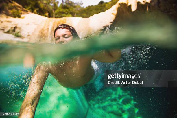 boy cooling off on a beautiful green pool in the river, swimming with underwater view on summertime in the catalan pyrenees. - hot boy body stock-fotos und bilder