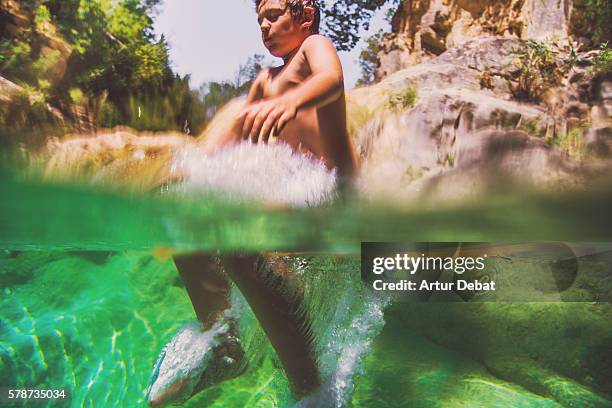 boy cooling off on a beautiful green pool in the river, jumping with underwater view on summertime in the catalan pyrenees. - hot boy body stock-fotos und bilder