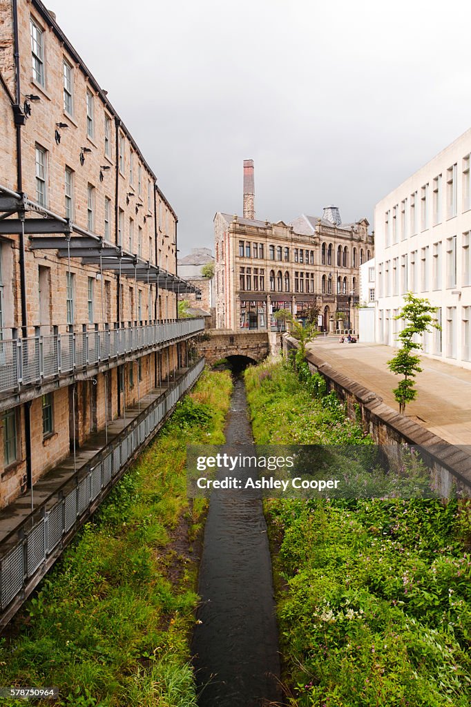 A straightened, channelised water course through Burnley Town centre between old buildings and the modern job centre,