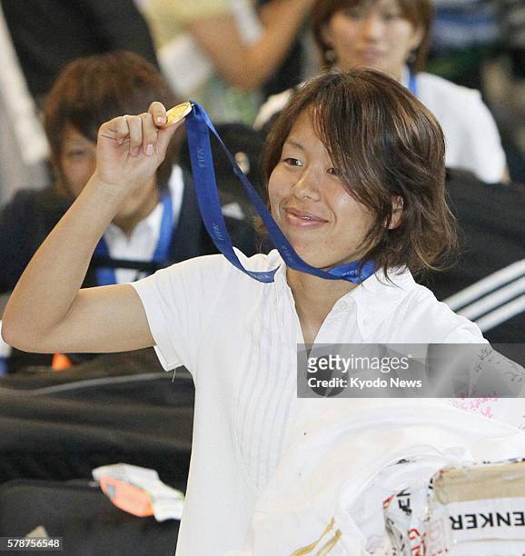 Japan - Azusa Iwashimizu of Japan's women's soccer team shows her gold medal to fans at Narita International Airport in Chiba Prefecture on July 19...