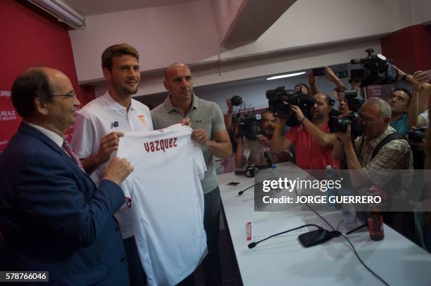 Sevilla FC football team's new player Argentine-born Italian midfielder Franco Vazquez holds his new jersey between Sevilla's President Jose Castro...