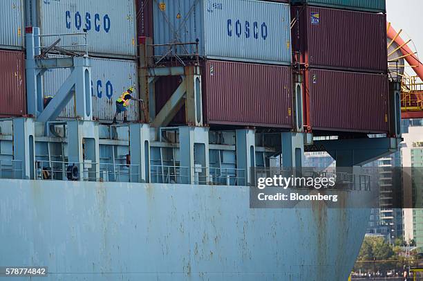 An employee assists in uploading shipping containers from a China Ocean Shipping Group Co. Cargo ship at the Port of Vancouver terminal in Vancouver,...