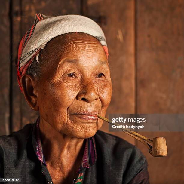 akha woman smoking a pipe in northern laos - akha woman stock pictures, royalty-free photos & images