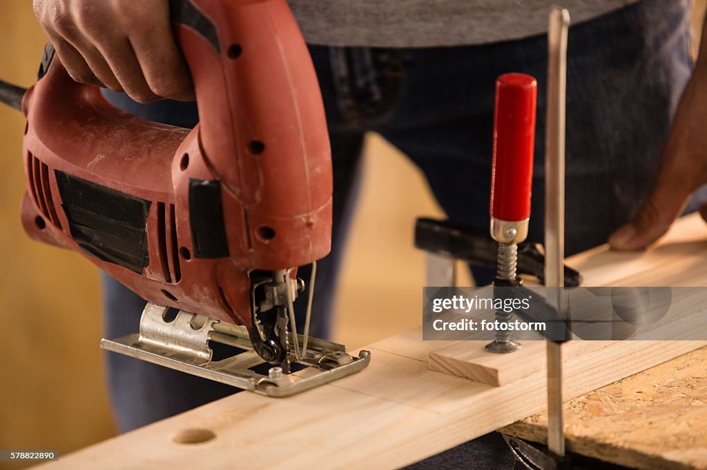 Carpenter cutting a wood using jigsaw cutter