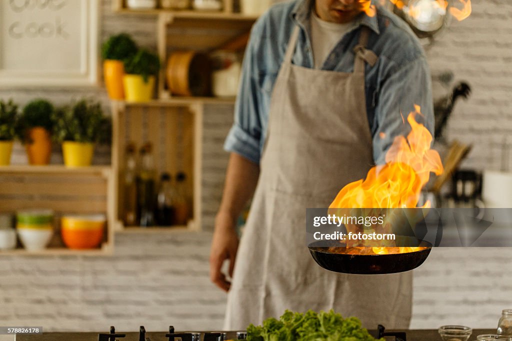 Man cooking with fire in kitchen
