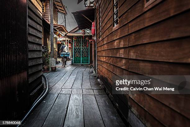 a man cycling in back alley of chew's jetty - georgetown - penang - malaysia - george town penang stockfoto's en -beelden
