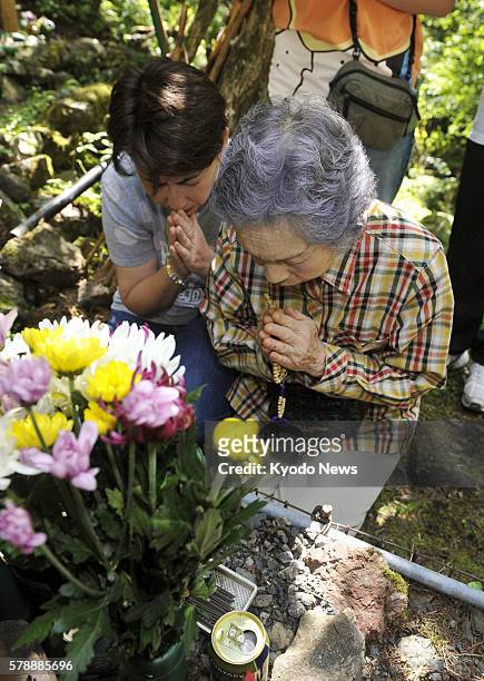 Japan - Relatives of victims of the 1985 Japan Airlines jumbo jet crash join their hands in prayers before a grave marking at the crash site called...