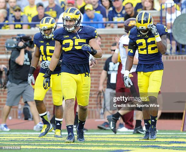 Michigan defensive players James Ross III, left, Joe Bolden, center, and Jarrod Wilson, right, walk off the field after Minnesota scored a third...