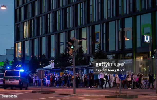 Police officers escort people with their hands raised from inside the shopping center as they respond to a shooting at the Olympia Einkaufzentrum at...