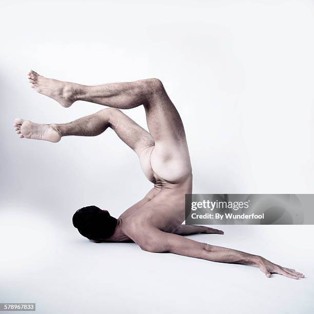 naked ballet dancer posing with his legs up - male gymnast stockfoto's en -beelden