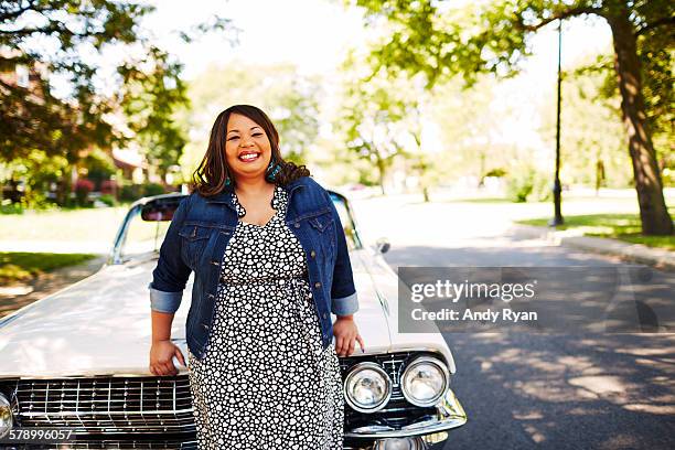 woman leaning on hood of vintage convertible. - fat black man stock-fotos und bilder