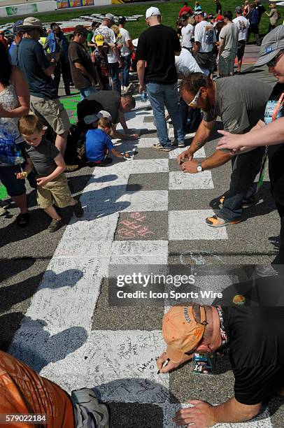 Fans sign the start/finish line during the Fan Takeover at Richmond International Raceway before the Sprint Cup Series Toyota Owners 400. Joey Logano...