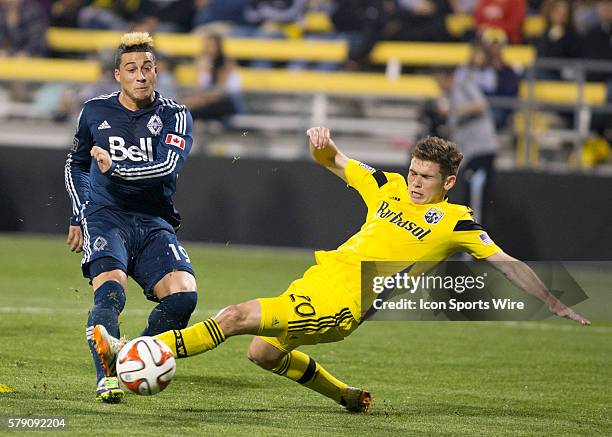 Erik Hurtado of the Vancouver Whitecaps FC taking a shot on goal while Wil Trapp of the Columbus Crew dives to block the shot with his foot during...
