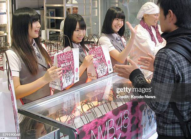 Japan - Three members of NMB48, an all-girl pop group based in Osaka's Namba district, serve customers at a croquette shop in Kobe, near Osaka, on...