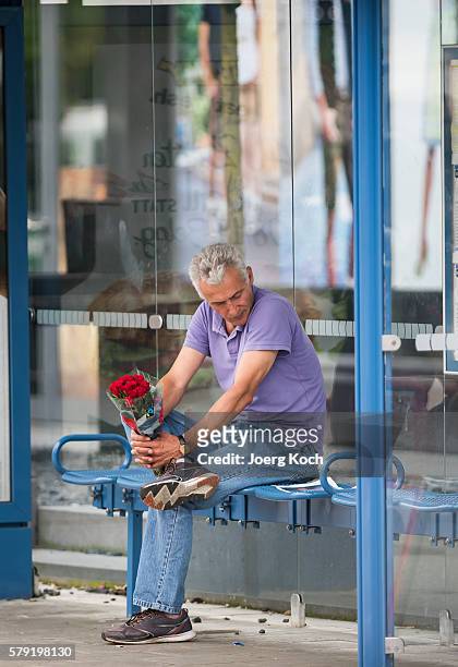 The father of one of the victims carries flowers and looks at a picture of his son while he waits outside the OEZ shopping center for a crisis...