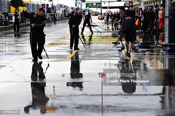 The Red Bull Racing team work to clear the rain from the pit box during qualifying for the Formula One Grand Prix of Hungary at Hungaroring on July...