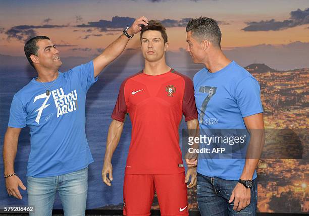 Portugese forward Cristiano Ronaldo and his brother Hugo Aveiro pose next to a wax statue representing Ronaldo during a visit to the new location of...