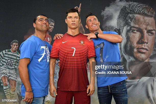 Portugese forward Cristiano Ronaldo and his brother Hugo Aveiro pose next to a wax statue representing Ronaldo during a visit to the new location of...