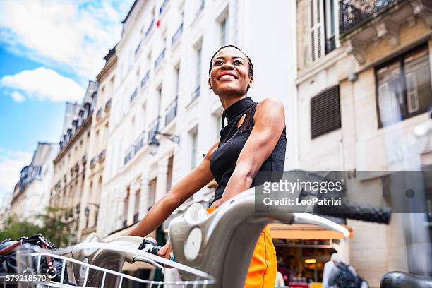 young woman taking a shared bicycle in paris - kombinerad mobilitet bildbanksfoton och bilder