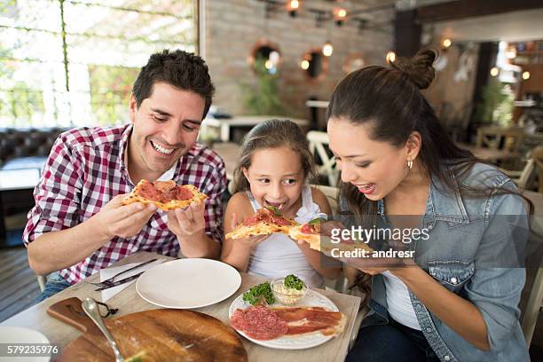 glückliche familie isst pizza im restaurant - family restaurant stock-fotos und bilder