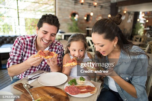 Happy family eating pizza at a restaurant Happy family eating pizza at a restaurant