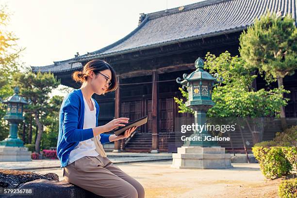 woman reading a digital tablet at a japanese temple - shinto shrine stock pictures, royalty-free photos & images