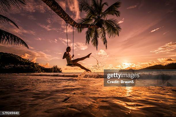 entspannte frau schwingen über dem meer ein sonnenuntergang strand. - seychellen stock-fotos und bilder