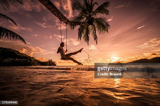 carefree woman swinging above the sea at sunset beach. - sunset beach stockfoto's en -beelden