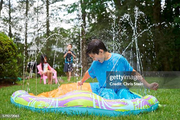 asian cousins playing on slip and slide - backyard water slide stock pictures, royalty-free photos & images