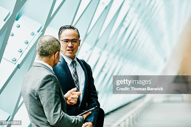 two businessmen discussing data on digital tablet - business mann tablet finance stock-fotos und bilder