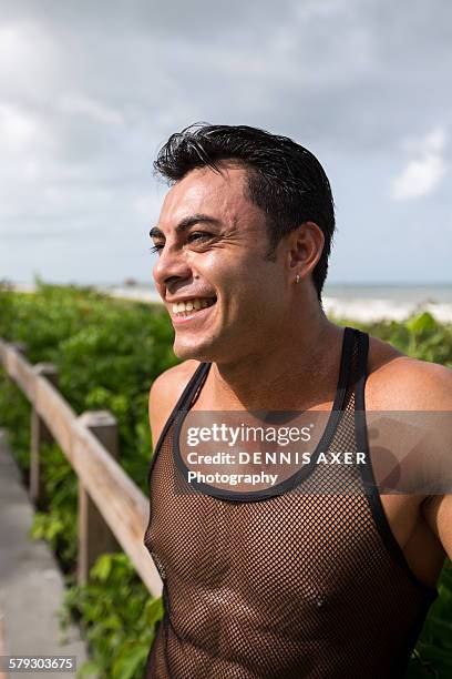 man at beach leaning against railing - brustwarze stock-fotos und bilder