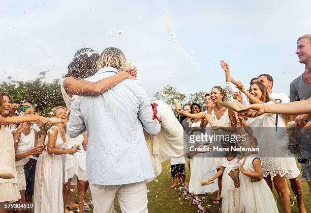 wedding guests tossing rice at newlyweds, outdoors - coniugi foto e immagini stock