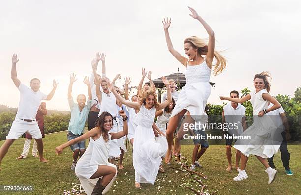 newlywed couple and guests jumping, outdoors - wedding party stock pictures, royalty-free photos & images