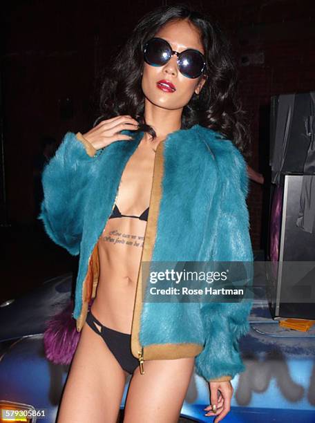 Portrait of an unidentified model, dressed in a black bikini, a blue fur coat, and sunglasses, poses at the launch party for the book 'Gloss: The...