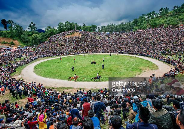 Villagers and visitors watch horse racing during the Torch Festival in Butuo county on July 22, 2016 in Liangshan Yi Autonomous Prefecture, Sichuan...