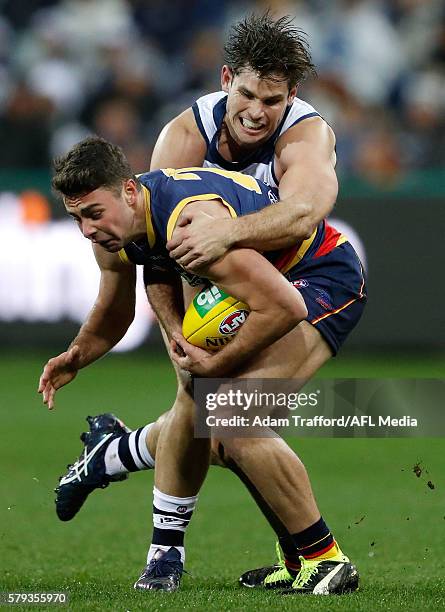 Rory Atkins of the Crows is tackled by Tom Hawkins of the Cats during the 2016 AFL Round 18 match between the Geelong Cats and the Adelaide Crows at...