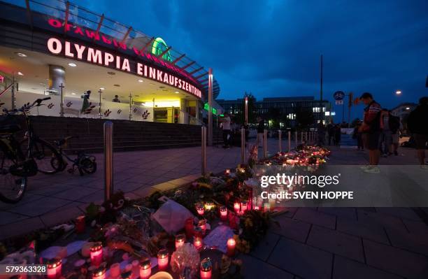 Candles and flowers lie in front of the Olympia-Einkaufszentrum shopping centre on July 23, 2016 in Munich, southern Germany, one day after a teenage...