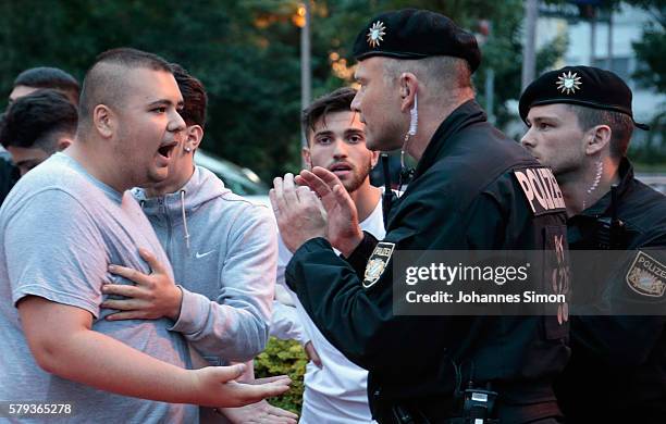 Riot police try to calm down teenage mourners shouting muslim slogans near the crime scene at OEZ shopping center the day after a shooting spree left...