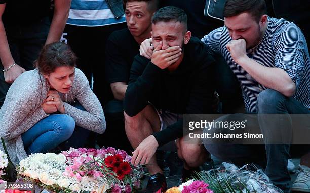 People mourn near the crime scene at OEZ shopping center the day after a shooting spree left nine victims dead on July 23, 2016 in Munich, Germany....