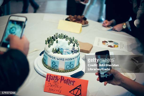 Undergraduate college students take pictures of a Harry Potter and the Deathly Hallows cake at the Johns Hopkins University's annual "Read It And Eat...