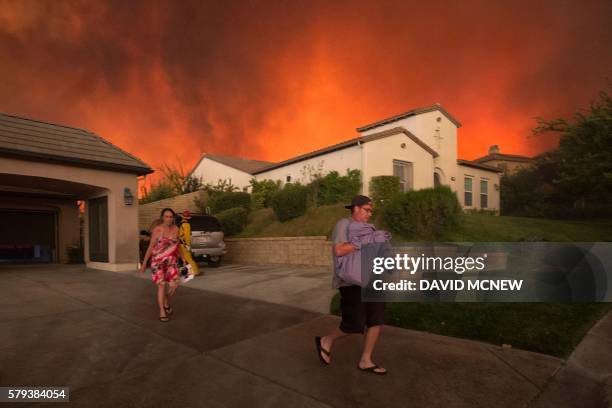 Residents flee their home as flames from the Sand Fire close in on July 23 2016 near Santa Clarita, California. Fueled by temperatures reaching about...